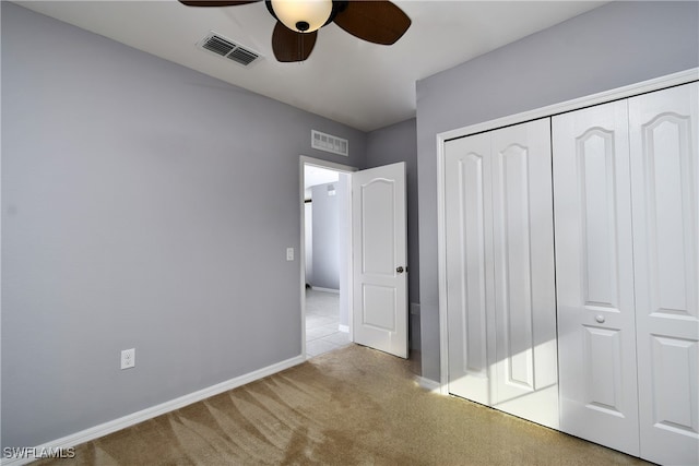 unfurnished bedroom featuring light carpet, ceiling fan, and a closet