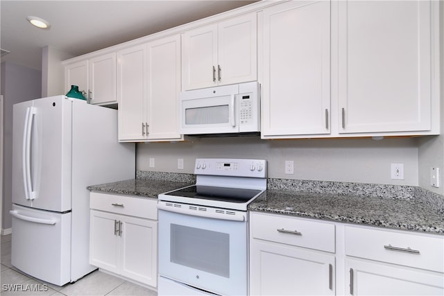 kitchen featuring dark stone countertops, white appliances, white cabinetry, and light tile patterned flooring