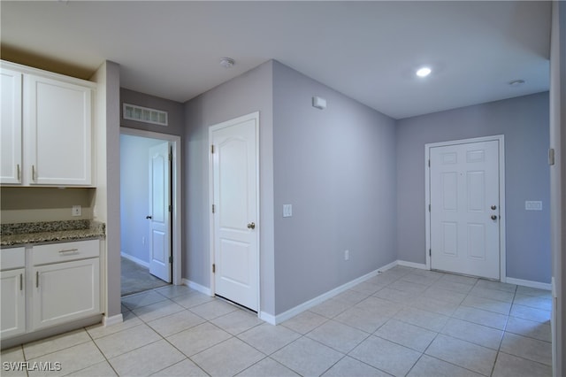 interior space featuring dark stone counters, light tile patterned floors, and white cabinets