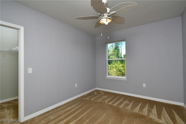 unfurnished bedroom featuring ceiling fan, a closet, carpet, and a walk in closet