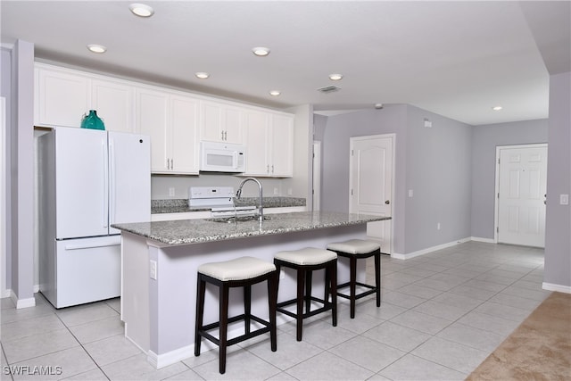 kitchen featuring white cabinets, an island with sink, and white appliances