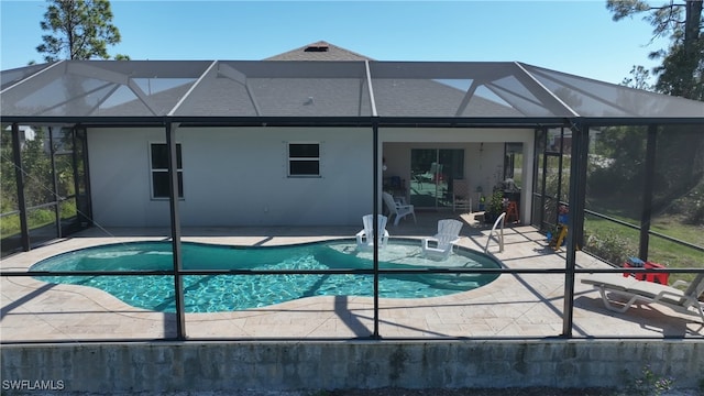 view of swimming pool featuring glass enclosure and a patio