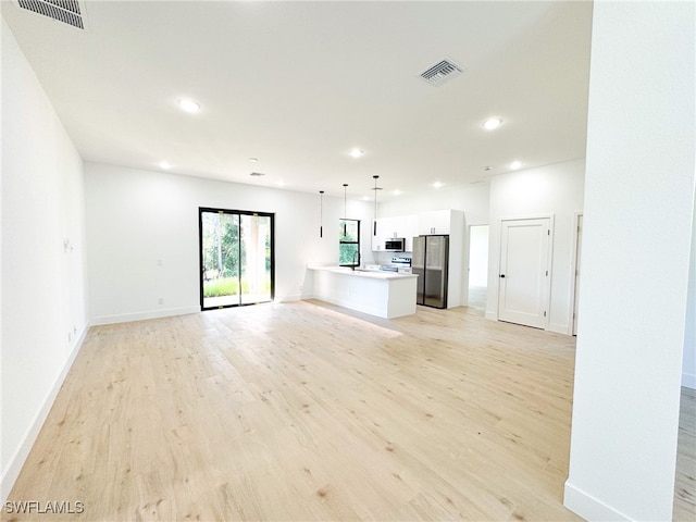 unfurnished living room featuring light wood-type flooring and sink