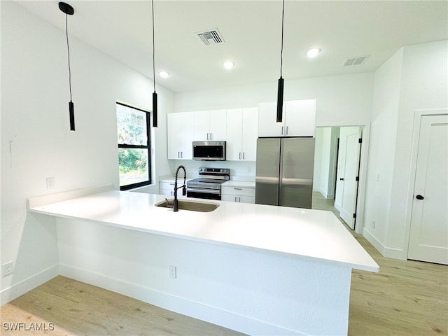 kitchen with light wood-type flooring, hanging light fixtures, white cabinetry, and stainless steel appliances