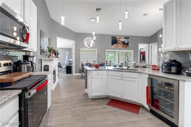 kitchen with wine cooler, stainless steel appliances, sink, and white cabinetry