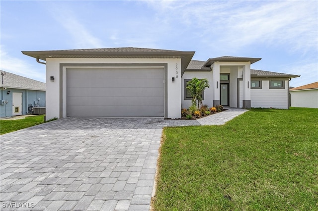 view of front of home with a garage, central AC, and a front yard