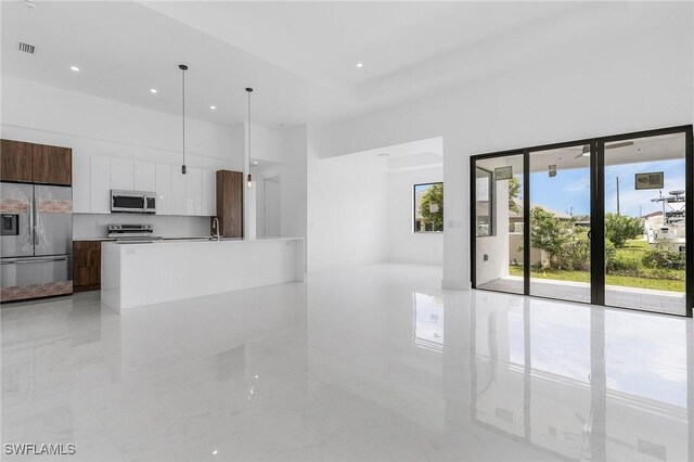 kitchen featuring pendant lighting, a kitchen island with sink, sink, white cabinetry, and stainless steel appliances