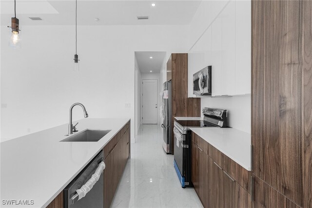 kitchen with white cabinets, appliances with stainless steel finishes, pendant lighting, and sink