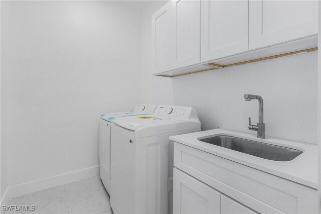 laundry area featuring separate washer and dryer, cabinets, and sink