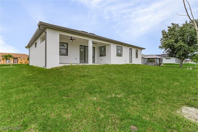 back of property with a lawn, a gazebo, and ceiling fan