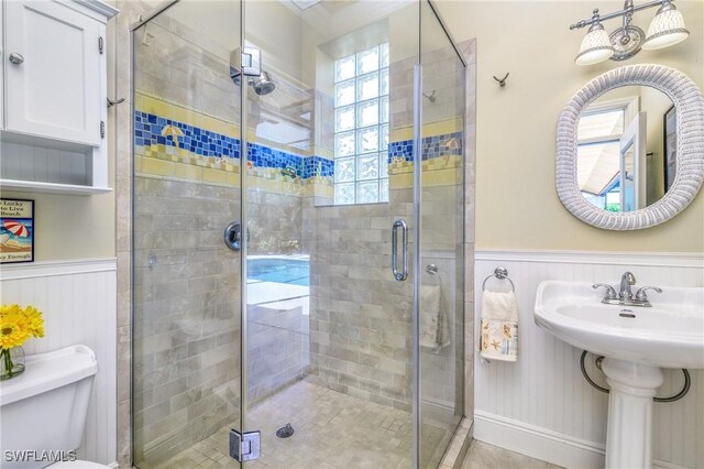 bathroom with toilet, a shower with door, and sink