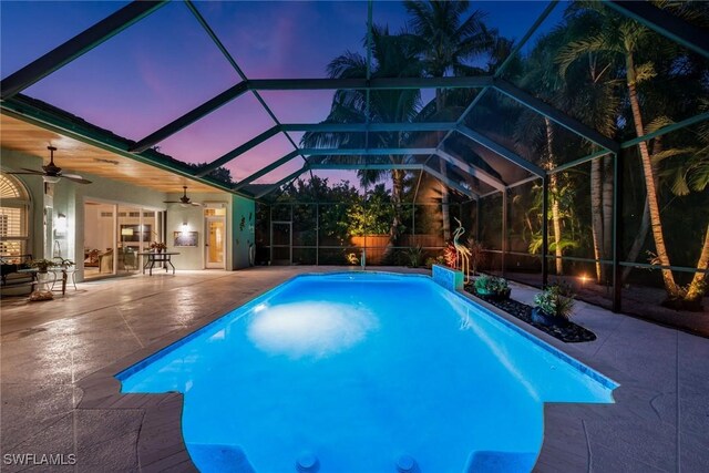 pool at dusk with a patio, ceiling fan, and a lanai