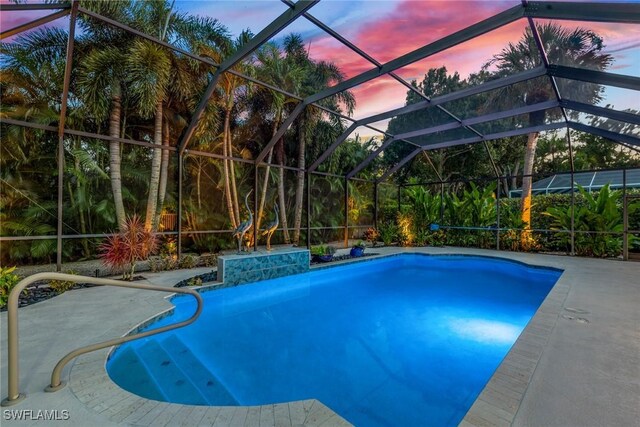 pool at dusk with a patio and glass enclosure