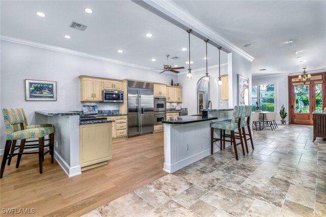 kitchen with kitchen peninsula, a breakfast bar, stainless steel appliances, and decorative light fixtures