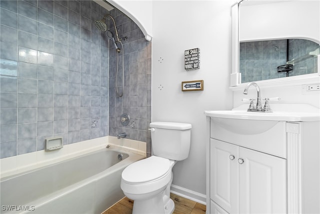 full bathroom with wood-type flooring, tiled shower / bath, vanity, and toilet