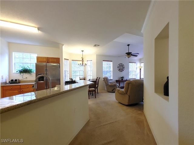 interior space with ceiling fan with notable chandelier, pendant lighting, crown molding, stainless steel refrigerator with ice dispenser, and light carpet