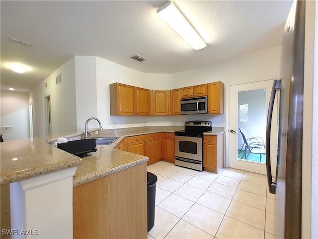 kitchen featuring appliances with stainless steel finishes, kitchen peninsula, light stone countertops, light tile patterned floors, and sink