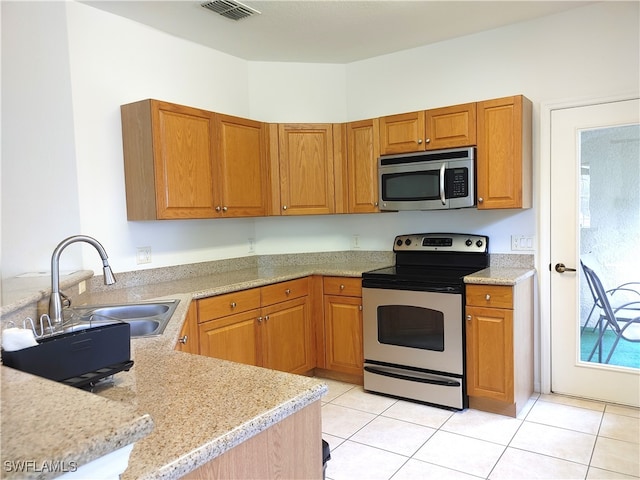 kitchen with light stone countertops, sink, appliances with stainless steel finishes, and light tile patterned floors