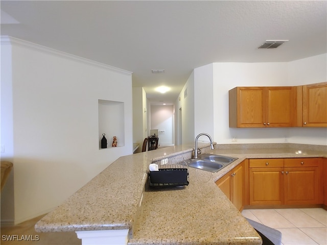 kitchen featuring sink, kitchen peninsula, light tile patterned floors, crown molding, and light stone countertops