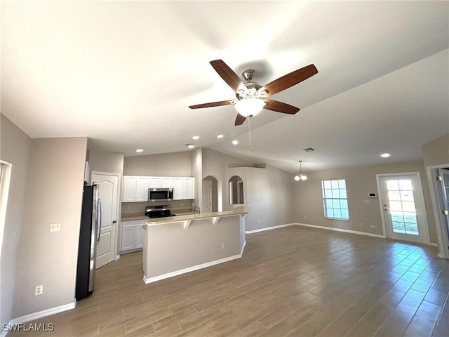 kitchen with lofted ceiling, light wood-style flooring, stainless steel appliances, white cabinetry, and open floor plan