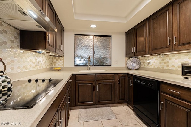 kitchen with wall chimney exhaust hood, sink, light tile patterned floors, a raised ceiling, and black appliances