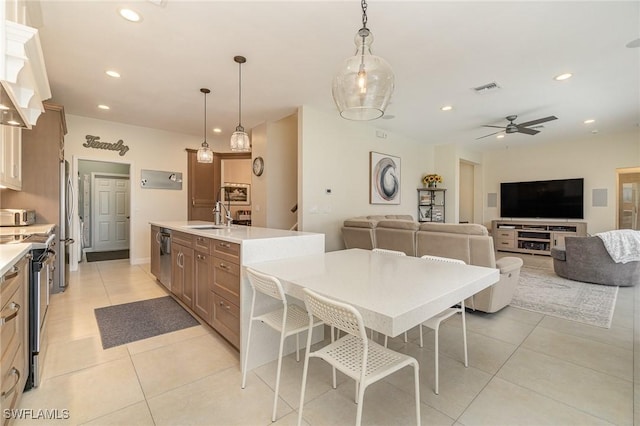 kitchen with sink, hanging light fixtures, ceiling fan, light tile patterned floors, and appliances with stainless steel finishes