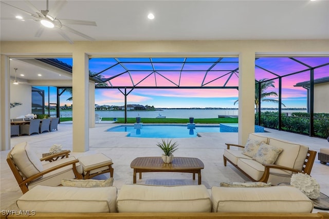 pool at dusk featuring a water view and ceiling fan