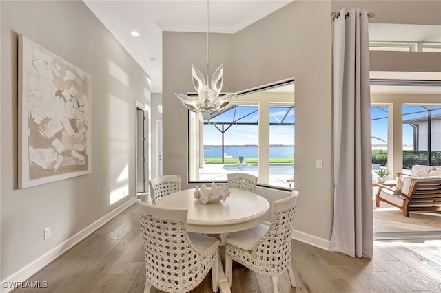 dining area with a chandelier, a water view, plenty of natural light, and ornamental molding