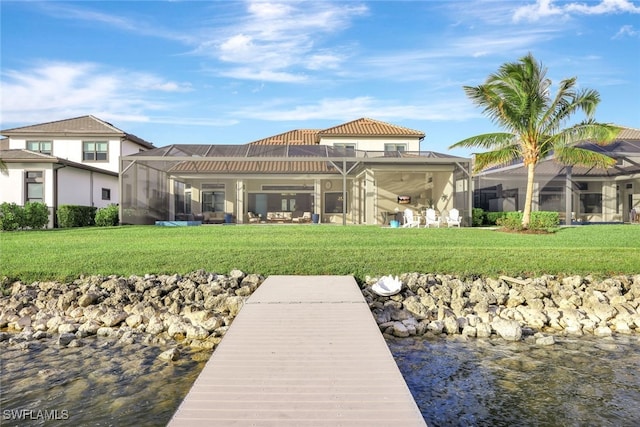 dock area featuring a lanai, a lawn, and a water view