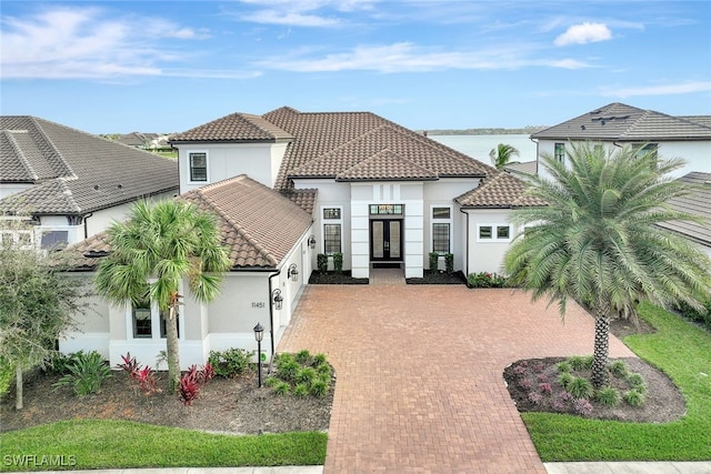 mediterranean / spanish-style home featuring french doors and a water view