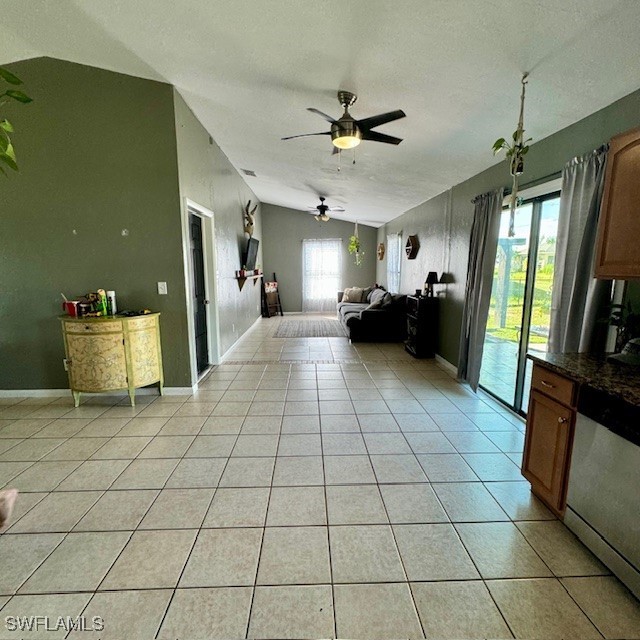 unfurnished living room with light tile patterned floors, a textured ceiling, lofted ceiling, and ceiling fan