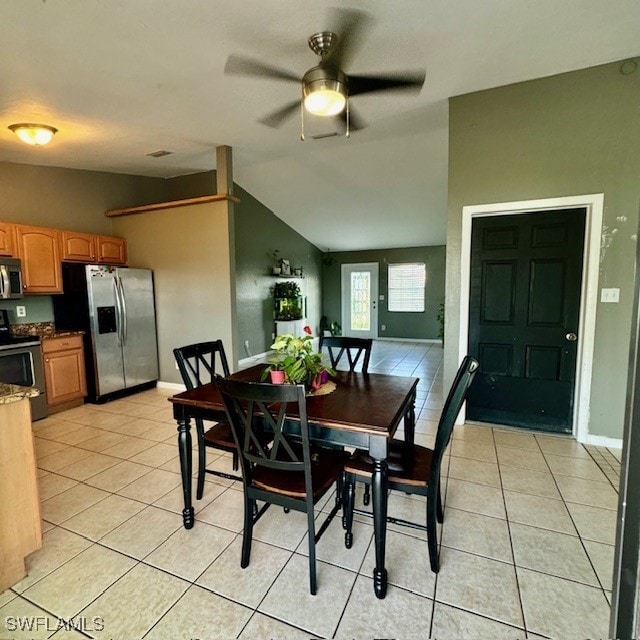 tiled dining space with ceiling fan and vaulted ceiling