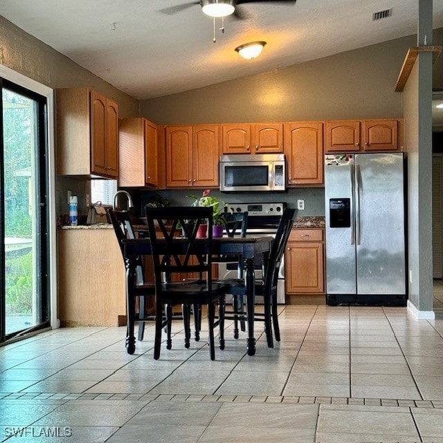 kitchen featuring vaulted ceiling, stainless steel appliances, light tile patterned floors, and ceiling fan