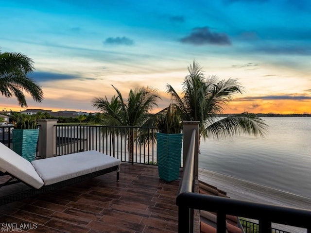 deck at dusk featuring a water view