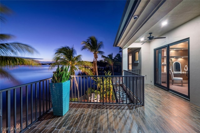 deck at dusk with a water view and ceiling fan