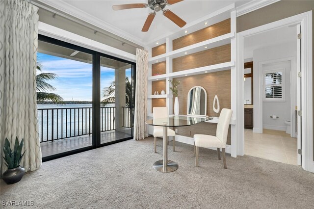 sunroom with ceiling fan and a water view