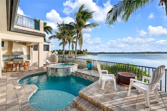 view of swimming pool with an in ground hot tub, pool water feature, a water view, a patio area, and grilling area