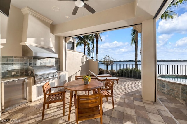 view of patio with area for grilling, an outdoor kitchen, a water view, and ceiling fan