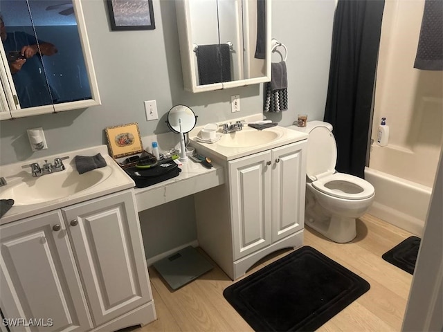 full bathroom with hardwood / wood-style floors, shower / tub combo with curtain, vanity, and toilet