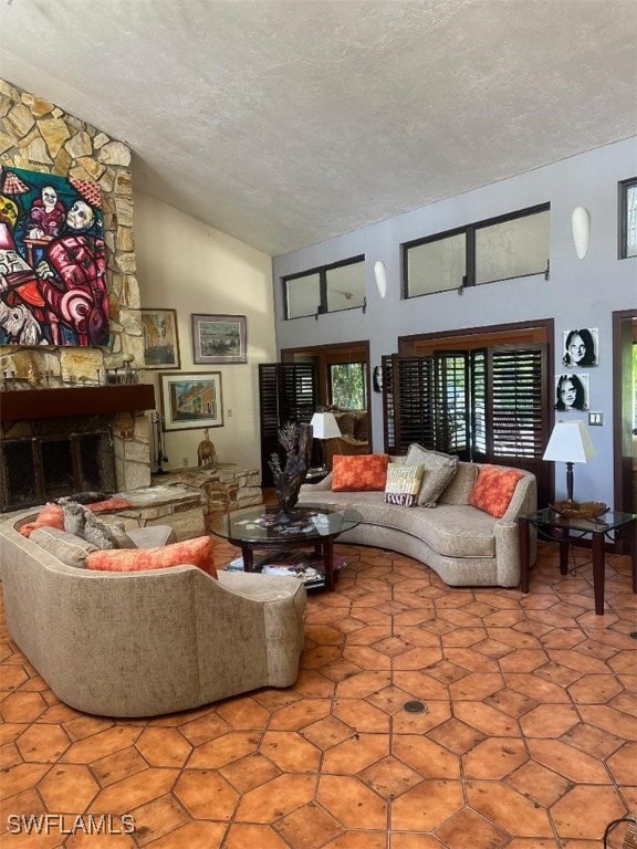 living room featuring a textured ceiling, a fireplace, and high vaulted ceiling