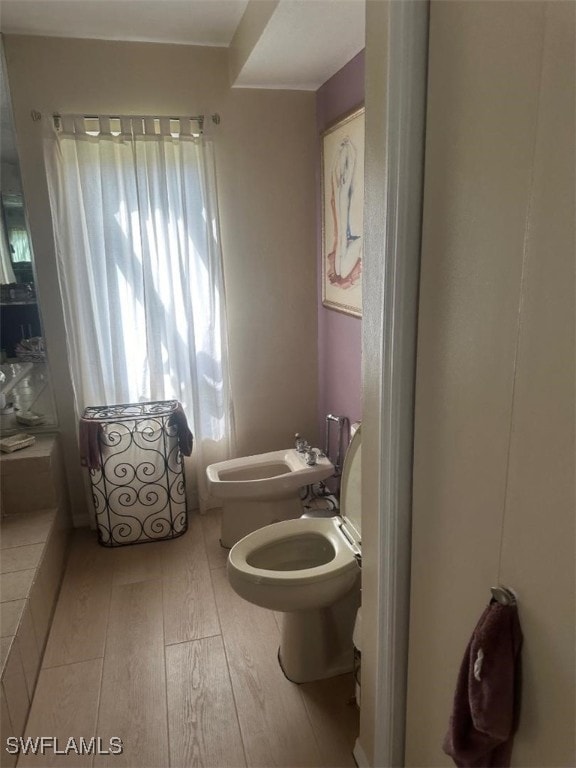 bathroom featuring hardwood / wood-style floors, toilet, a bidet, and a wealth of natural light