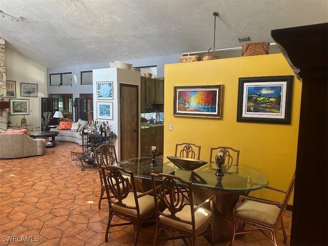 tiled dining area with a textured ceiling and lofted ceiling