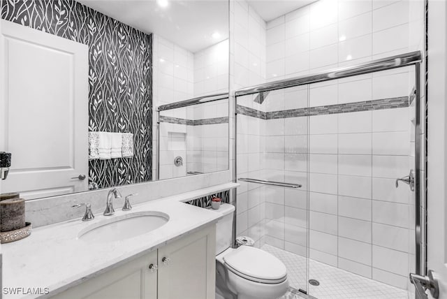 bathroom featuring vanity, a shower with shower door, and toilet