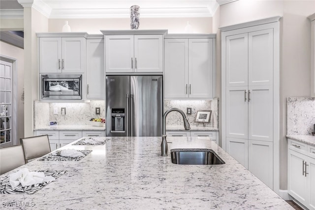 kitchen featuring light stone countertops, appliances with stainless steel finishes, sink, and ornamental molding