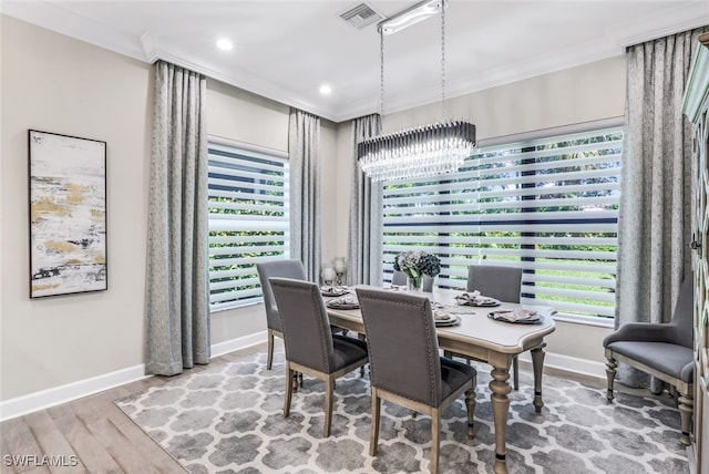 dining space with crown molding, wood-type flooring, and a notable chandelier