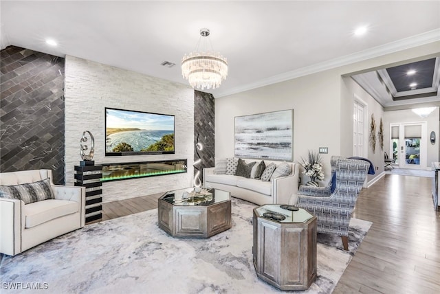 living room with crown molding, a chandelier, and light hardwood / wood-style floors