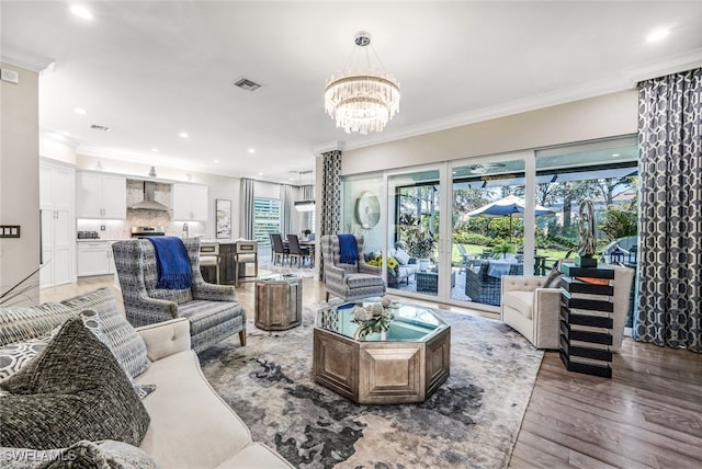 living room with hardwood / wood-style flooring, crown molding, and a notable chandelier