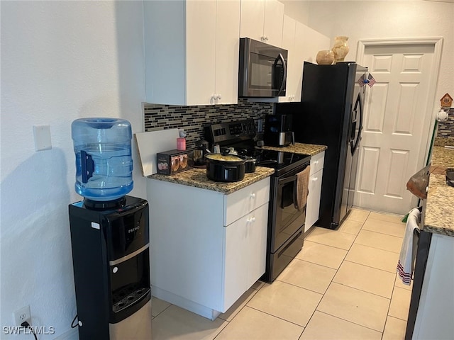 kitchen with dark stone counters, stainless steel range with electric cooktop, white cabinetry, decorative backsplash, and light tile patterned floors