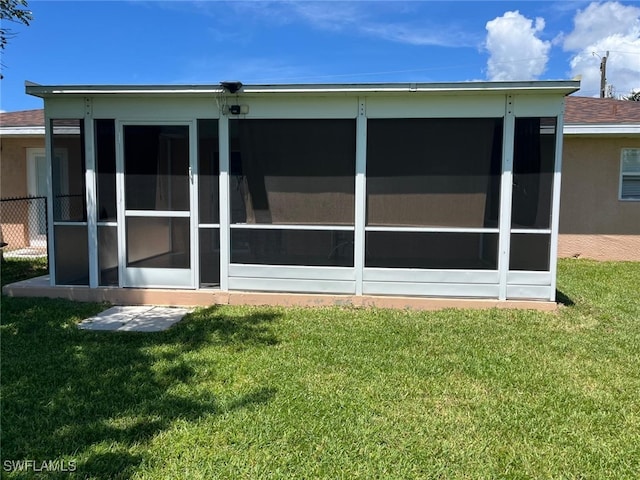 back of property with a lawn and a sunroom