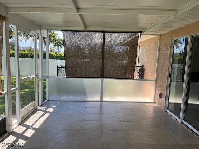 unfurnished sunroom featuring beamed ceiling